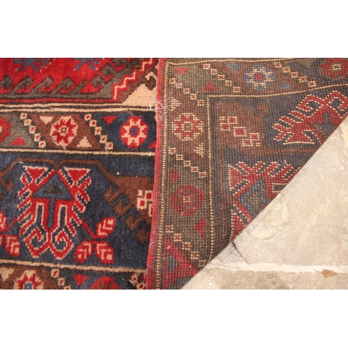 385 - A Turkish hand knotted wool rug, in red, blue and ivory colourways, the central lozenge shaped field... 