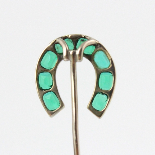 82 - An early 20th century green stone set stick pin, the horse shoe shaped head set with eight cushion c... 