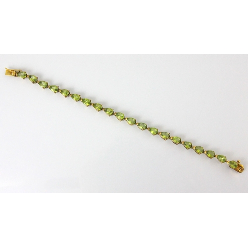 87 - An untested peridot bracelet, the twenty pear cut untested peridots within a gold plated mount, with... 