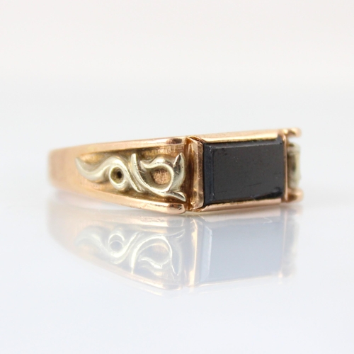 88 - A yellow metal dress ring, the rectangular slice of onyx coloured stone leading to applied stylised ... 