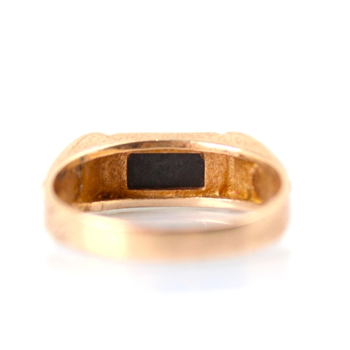 88 - A yellow metal dress ring, the rectangular slice of onyx coloured stone leading to applied stylised ... 