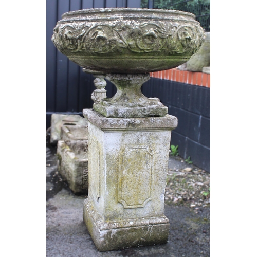 524 - A reconstituted garden urn and plinth, the urn of squat form, moulded in relief with foliate detail,... 