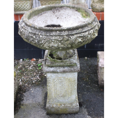 524 - A reconstituted garden urn and plinth, the urn of squat form, moulded in relief with foliate detail,... 