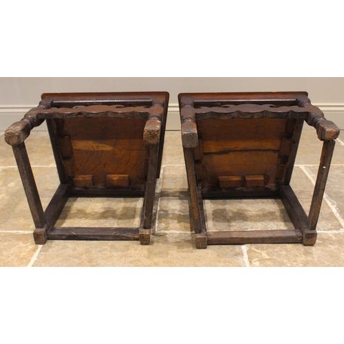 432 - A pair of early 18th century oak hall chairs, each with a scrolled openwork pediment over a panel ba... 