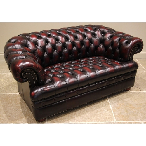 517 - An ox blood red leather Chesterfield type two seater sofa, late 20th/early 21st century, of typical ... 