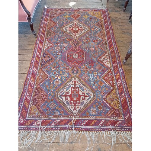 391 - A Persian Heriz type hand knotted wool rug, the central blue ground with three linked octagonal meda... 