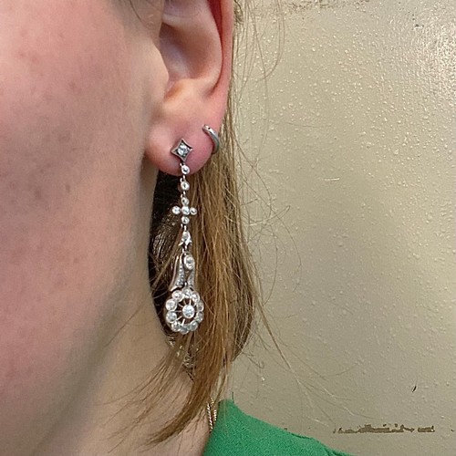 68 - A pair of early 20th century diamond drop earrings, the stylised flowerhead set with eleven round cu... 