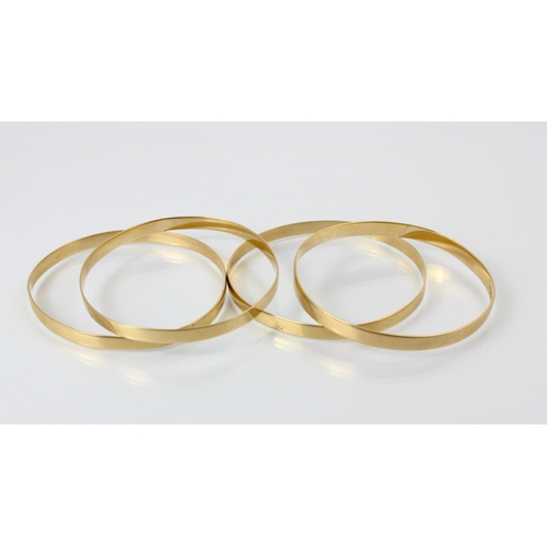 103 - A set of four South African yellow metal bangles, of plain polished form, stamped to interior ‘9ct’ ... 