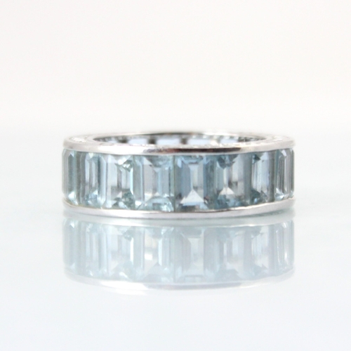 109 - A late 20th century untested aquamarine full eternity ring, the eighteen rectangular cut blue stones... 