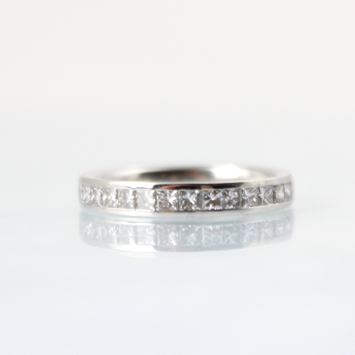 110 - A diamond half eternity ring, the fourteen princess cut diamonds channel set in white metal, with pl... 