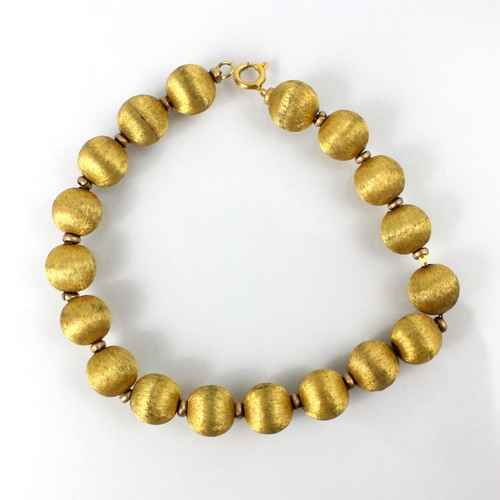 113 - A yellow metal trace link bracelet, the bracelet with eighteen spherical beads with gilt engraved de... 