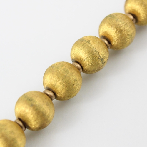 113 - A yellow metal trace link bracelet, the bracelet with eighteen spherical beads with gilt engraved de... 