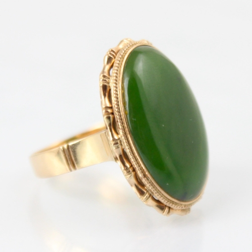 118 - A yellow metal nephrite dress ring, the oval shaped cabochon within a yellow metal bamboo style moun... 