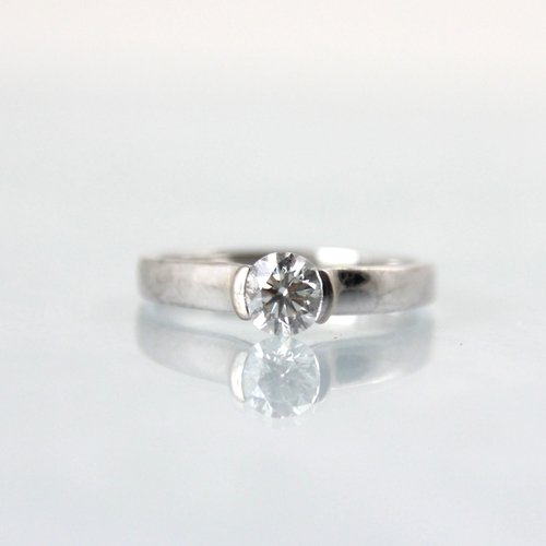 123 - An 18ct white gold diamond solitaire ring, the central brilliant cut diamond within partial rub over... 