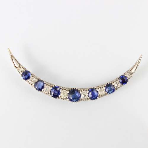 130 - An early 20th century diamond and untested sapphire crescent brooch, the seven graduated cushion cut... 