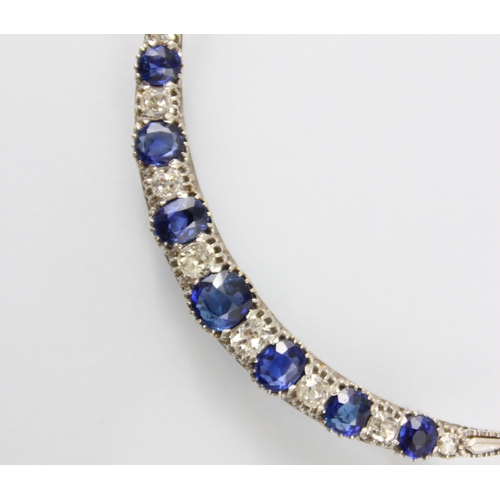 130 - An early 20th century diamond and untested sapphire crescent brooch, the seven graduated cushion cut... 