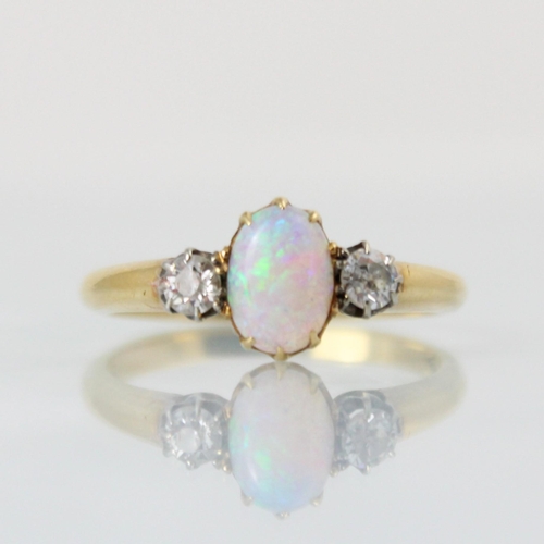 146 - An early 20th century opal and diamond three stone ring, the central oval opal cabochon with old cut... 