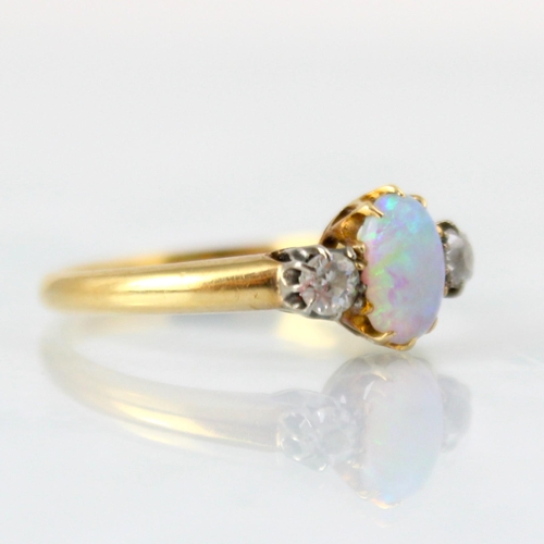 146 - An early 20th century opal and diamond three stone ring, the central oval opal cabochon with old cut... 