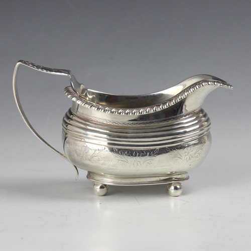 29 - A 19th century white metal milk jug, of compressed oval from with floral engraving upon four ball fe... 