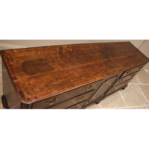 698 - A George III oak and mahogany cross banded Lancashire dresser base, the plank top with rounded front... 