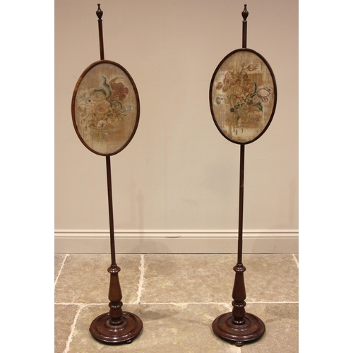 729 - A pair of 19th century mahogany pole screens, each with an urn shaped finial upon a slender pole sup... 