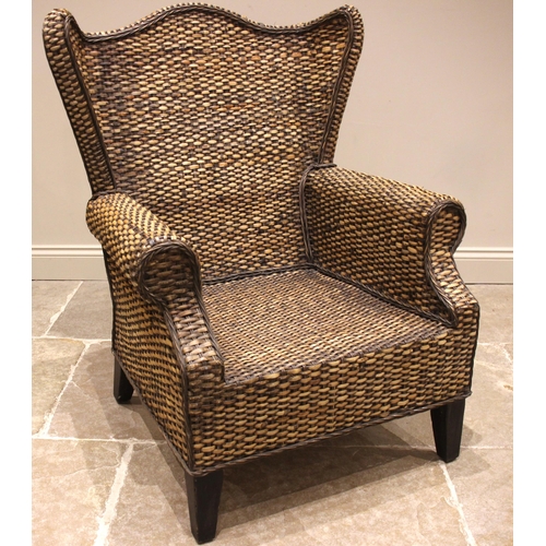 788 - An American style wicker wingback armchair, 20th century, with a serpentine back rest and shaped win... 