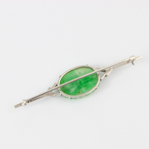 137 - An Art Deco jade brooch, the central oval carved panel depicting fruit and foliage, set in a white m... 