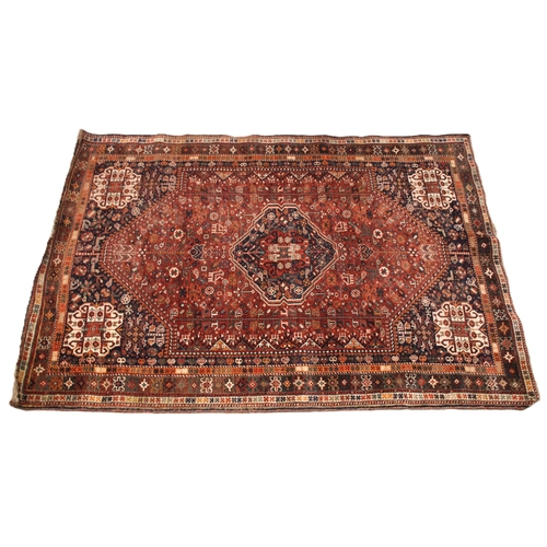 634 - A Persian Qashqai rug, in red, blue and ivory colourways, the central medallion upon a red field fil... 