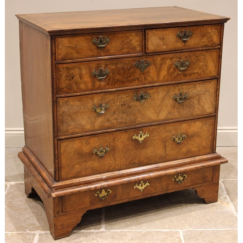 686 - A George I walnut chest on stand, the quarter veneered and feather banded top over an arrangement of... 