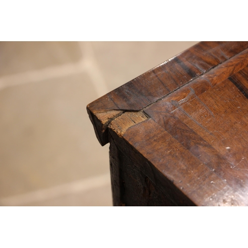 686 - A George I walnut chest on stand, the quarter veneered and feather banded top over an arrangement of... 