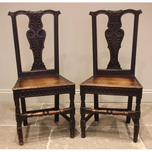 688 - A pair of carved oak hall chairs, 19th century, each with a profusely carved vasiform splat over a b... 