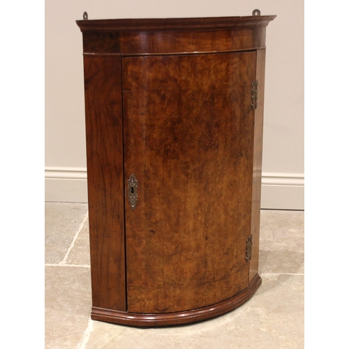 759 - A burr walnut bow fronted wall mounted corner cupboard, 19th century, the moulded pediment over a si... 