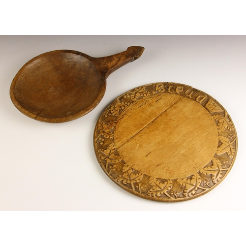 556 - A circular carved sycamore bread board, 19th century, the border relief carved with leaves, 'Bread' ... 