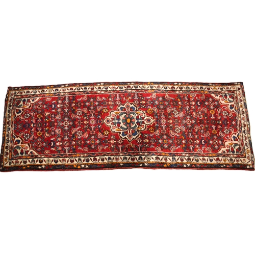 641 - A Caucasian hand knotted wool runner, the vibrant red ground with a central medallion and an all ove... 