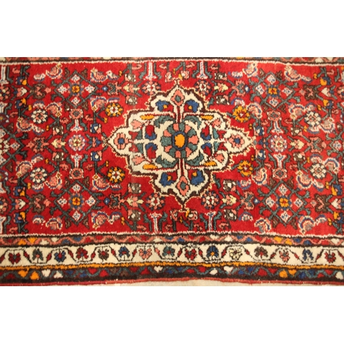 641 - A Caucasian hand knotted wool runner, the vibrant red ground with a central medallion and an all ove... 