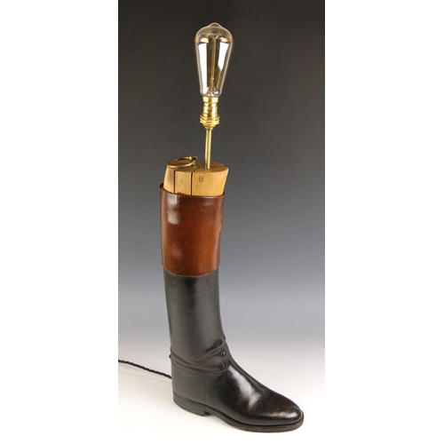 611 - A novelty lamp, the light fitting set to a wooden boot tree within a black and tan leather riding bo... 