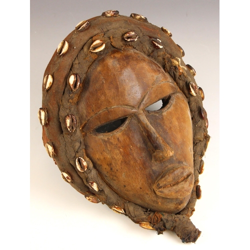 529 - A Dan Tribe mask (Dean Gle), with cowrie shell mounted headdress, 30cm long, with a South African Zu... 