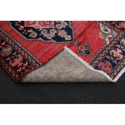 645 - A washed red ground Persian Surok village rug, with a large floral medallion design, 205cm x 122cm