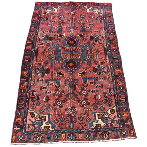 647 - A terracotta ground Persian village rug, with a bespoke design embellished with duck egg blue highli... 