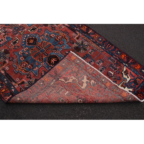 647 - A terracotta ground Persian village rug, with a bespoke design embellished with duck egg blue highli... 