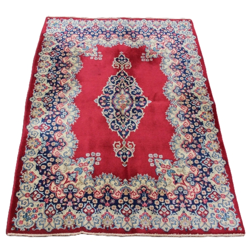 648 - A rich red ground Persian Kerman rug, with a central floral medallion within a broad floral border, ... 