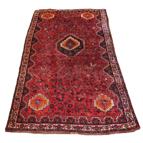 651 - A red rich ground Persian Qashqai tribal rug, the traditional all over design, floral and zoomorphic... 