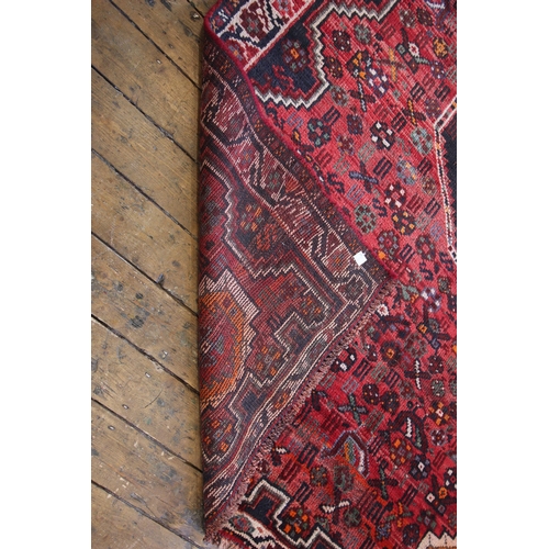 651 - A red rich ground Persian Qashqai tribal rug, the traditional all over design, floral and zoomorphic... 