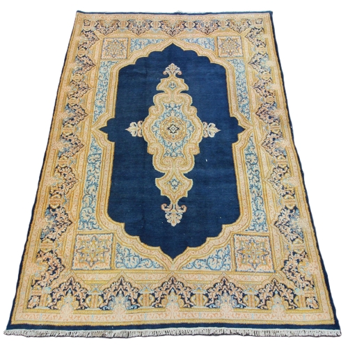 654 - A rich blue ground Kerman rug, with a bespoke medallion pattern, within a ogee shaped floral border,... 