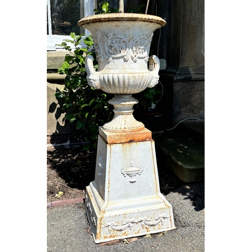 797 - A pair of cast iron white painted urns and pedestals, in the manner of Andrew Handyside, each of typ... 