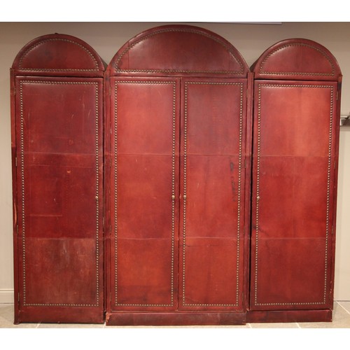 781 - An impressive and large red leather wardrobe, mid 20th century, of triple arched form, the pair of c... 