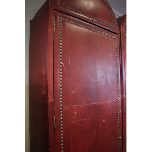 781 - An impressive and large red leather wardrobe, mid 20th century, of triple arched form, the pair of c... 