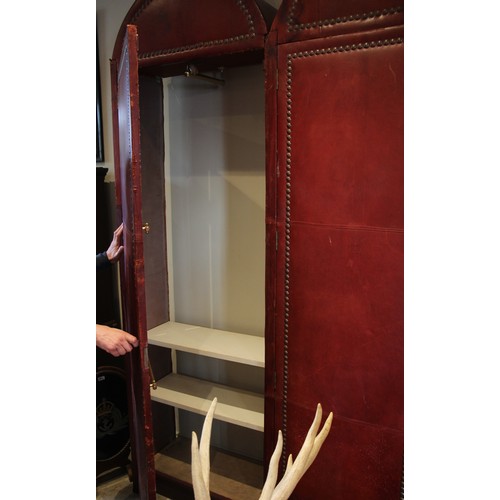 781 - An impressive and large red leather wardrobe, mid 20th century, of triple arched form, the pair of c... 