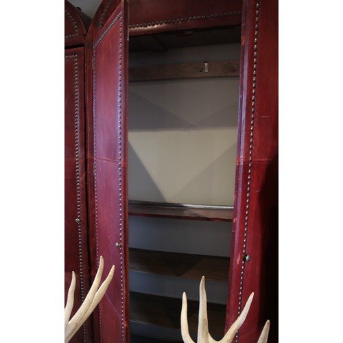 781 - An impressive and large red leather wardrobe, mid 20th century, of triple arched form, the pair of c... 