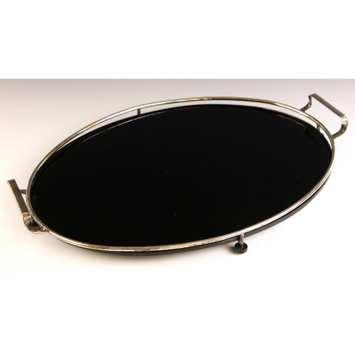 106 - A silver plated Art Deco style tray, the oval black glass base with silver plated mount and twin han... 